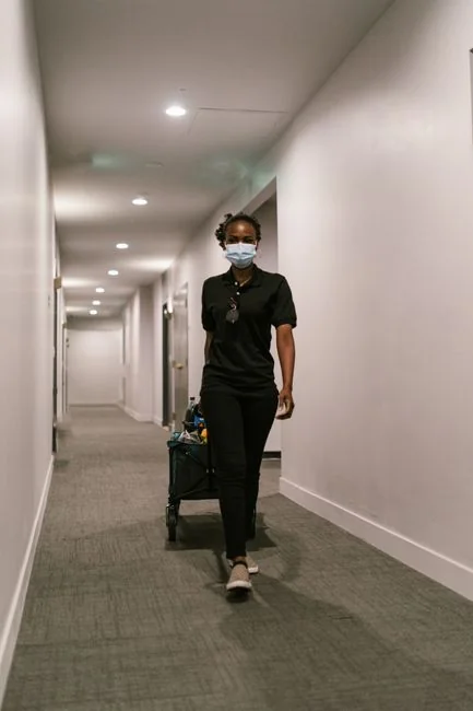 a-woman-in-a-green-shirt-and-black-gloves-vacuuming-a-gray-ottoman-5txz228u4eo