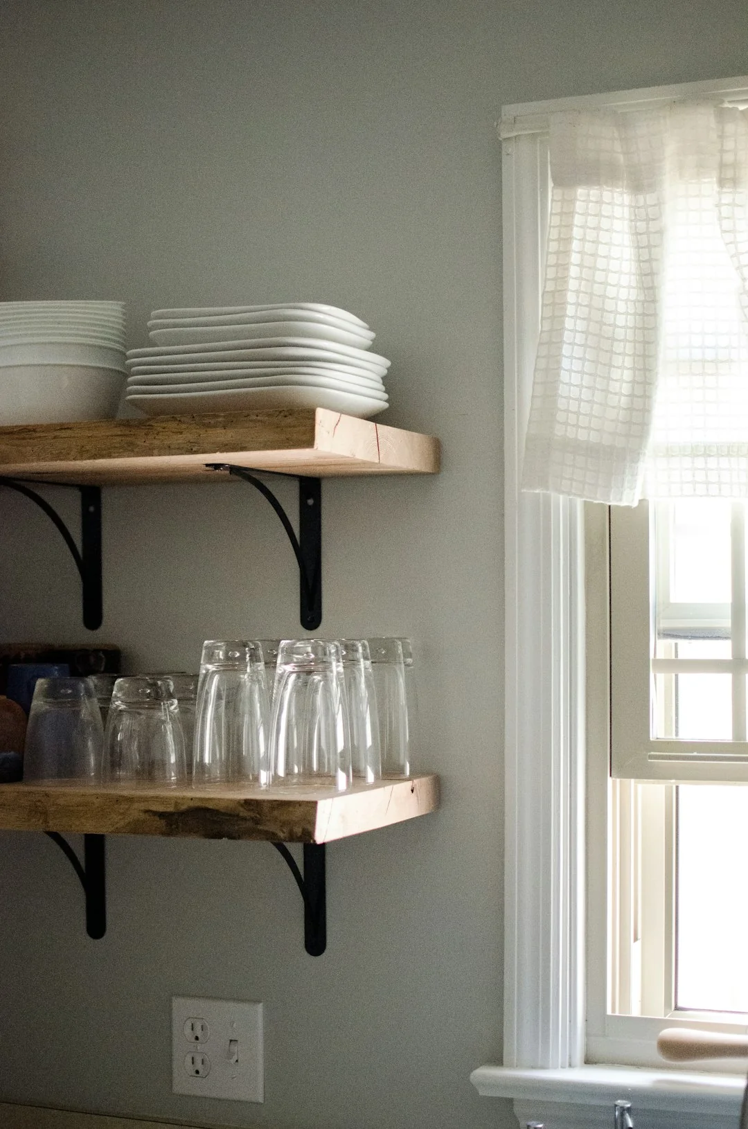 Canapé recouvert d’un drap, lampadaire et cartons emballés dans une pièce claire et spacieuse d’une maison contemporaine neuve